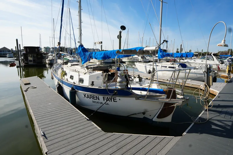The Image of 1975 Westsail 32 sailboat docked in marina, sunny day, blue covers, calm water. - 0