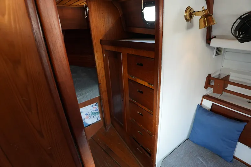 Slide: The Image of 1975 Westsail 32 interior with wooden cabinetry, cozy sleeping area, and nautical decor. - 12