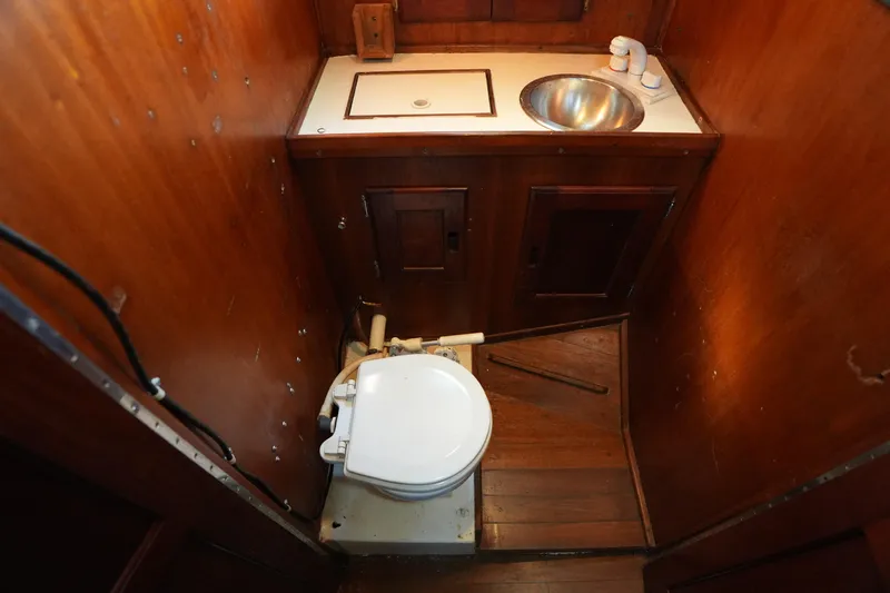 Slide: The Image of 1975 Westsail 32 boat bathroom with wooden interior, sink, and marine toilet. - 13