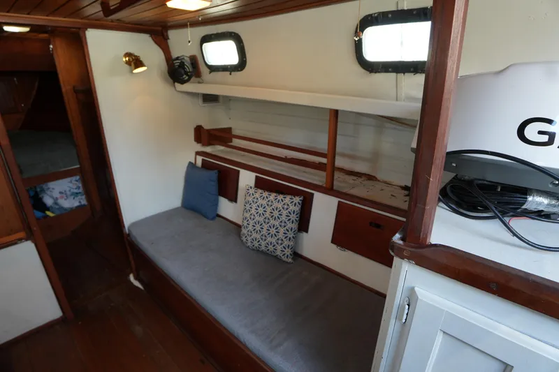 Slide: The Image of 1975 Westsail 32 interior with cozy seating, wooden accents, and nautical decor. - 15