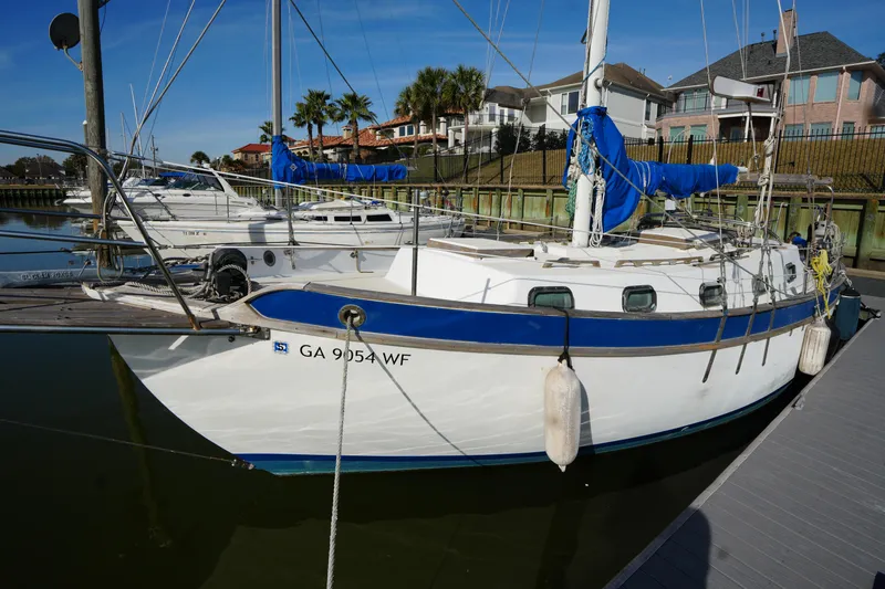 Slide: The Image of 1975 Westsail 32 sailboat docked, featuring blue accents and fenders, in a marina setting. - 2