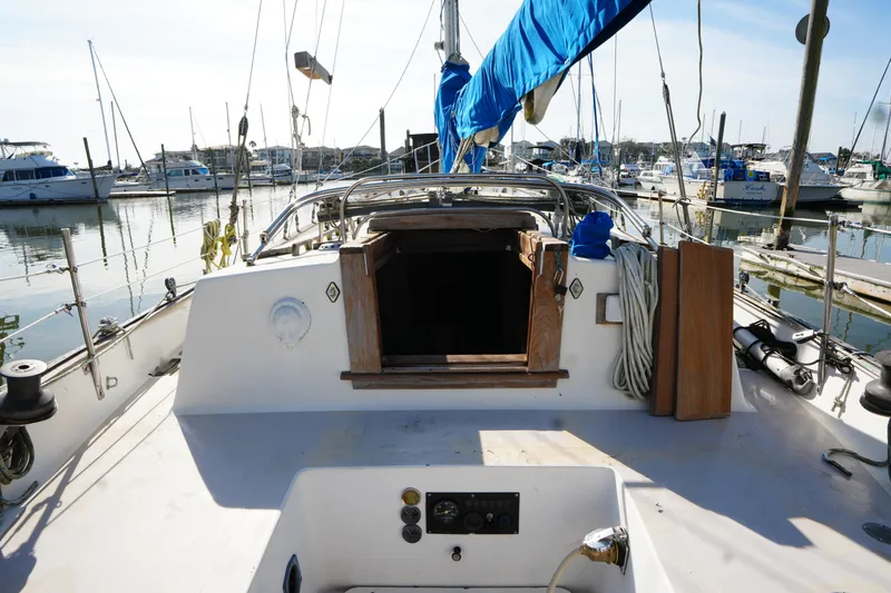 Slide: The Image of 1975 Westsail 32 sailboat docked at marina, featuring open cabin and blue sail cover. - 8