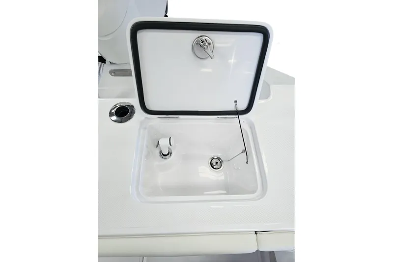 Slide: The Image of Open storage compartment on 2026 Jupiter 26 boat, featuring a secure latch and drain plug. - 19
