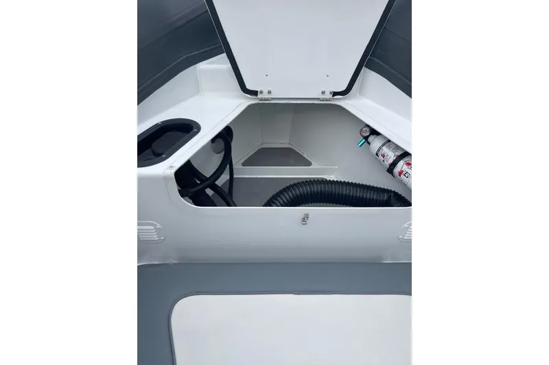 Slide: The Image of Open storage compartment in 2019 Highfield 640 Deluxe boat, featuring hoses and a fire extinguisher. - 29