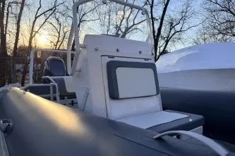 Slide: The Image of 2019 Highfield Patrol 660 boat with seating, set against a sunset and trees backdrop. - 3