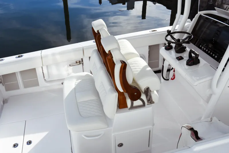 Slide: The Image of Luxury seating and helm of 2026 Jupiter 30 boat, featuring white upholstery and modern controls. - 17