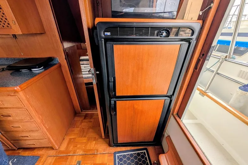 Slide: The Image of 1987 DeFever Trawler interior with wooden cabinetry and refrigerator. - 13