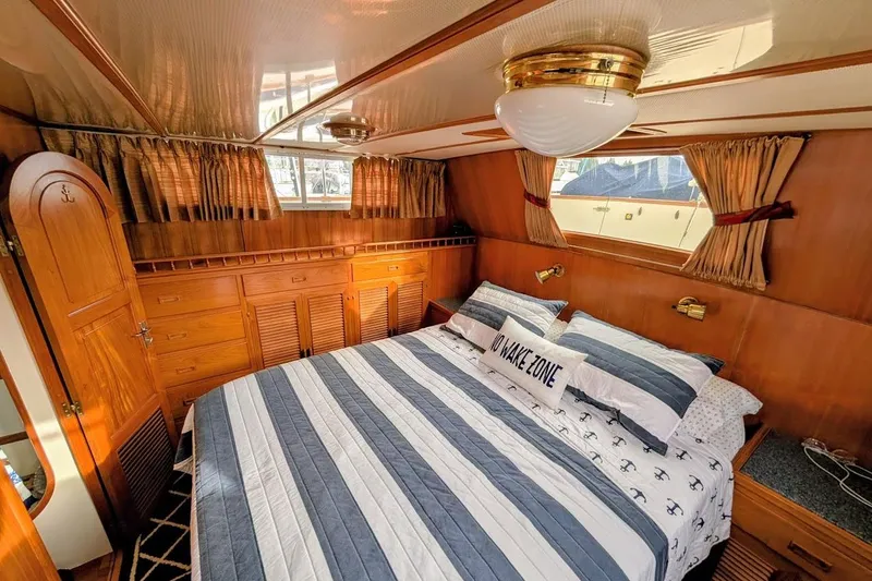 Slide: The Image of Luxurious 1987 DeFever Trawler bedroom with striped bedding and wooden cabinetry. - 15