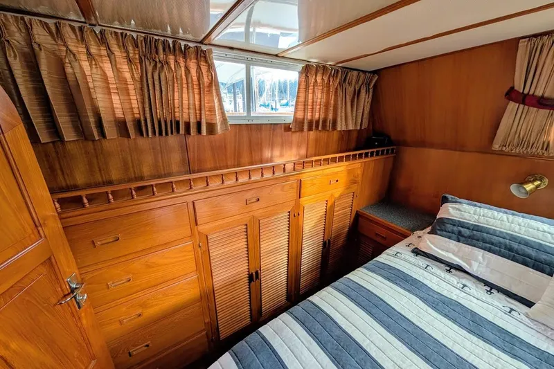 Slide: The Image of 1987 DeFever Trawler cabin interior with wood paneling, bed, and storage cabinets. - 16