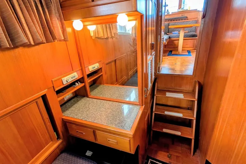 Slide: The Image of 1987 DeFever Trawler interior with wooden cabinetry, mirror, and stairs leading to dining area. - 17