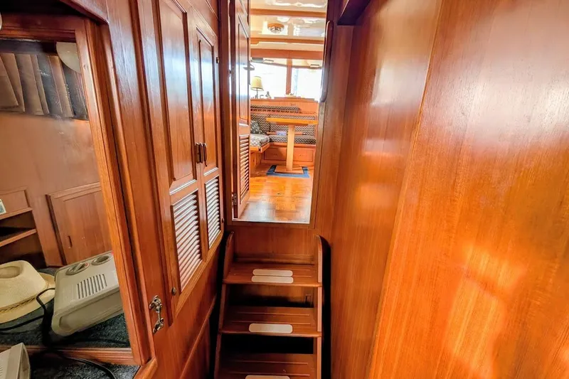 Slide: The Image of 1987 DeFever Trawler interior with wooden stairs and cabinetry, leading to a cozy seating area. - 21
