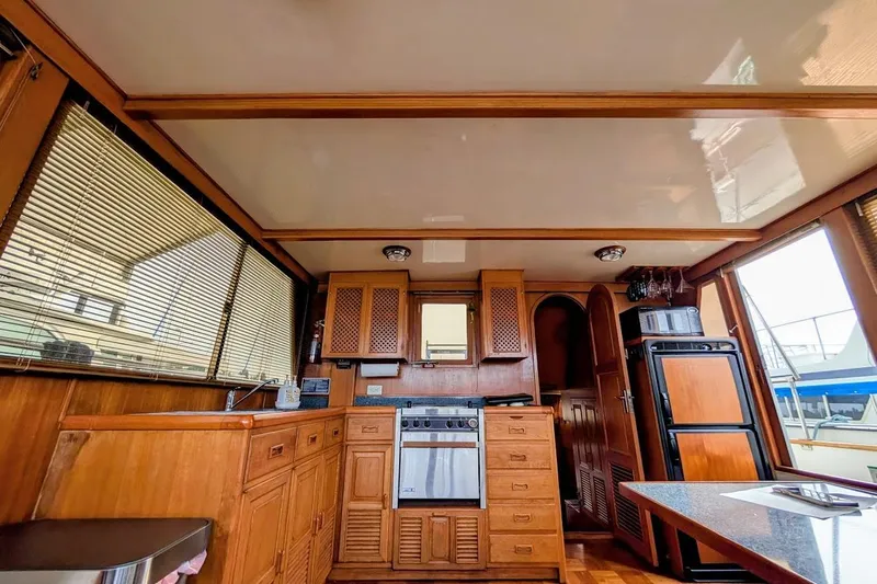Slide: The Image of 1987 DeFever Trawler interior with wooden cabinetry, kitchen appliances, and large windows. - 23