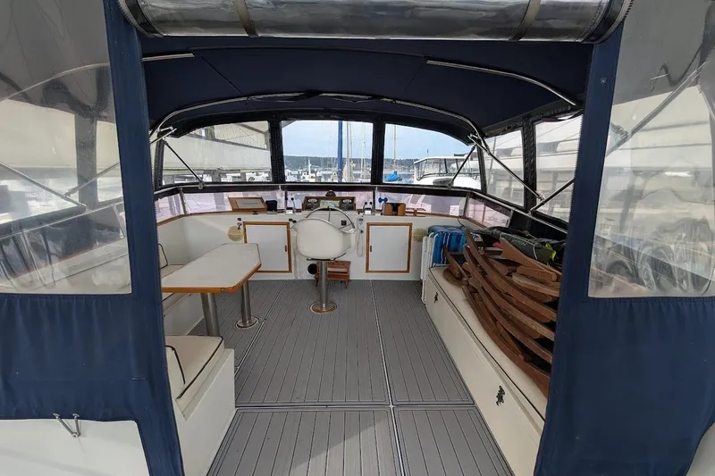 Slide: The Image of 1987 DeFever Trawler interior with seating, table, and helm station in a marina setting. - 31