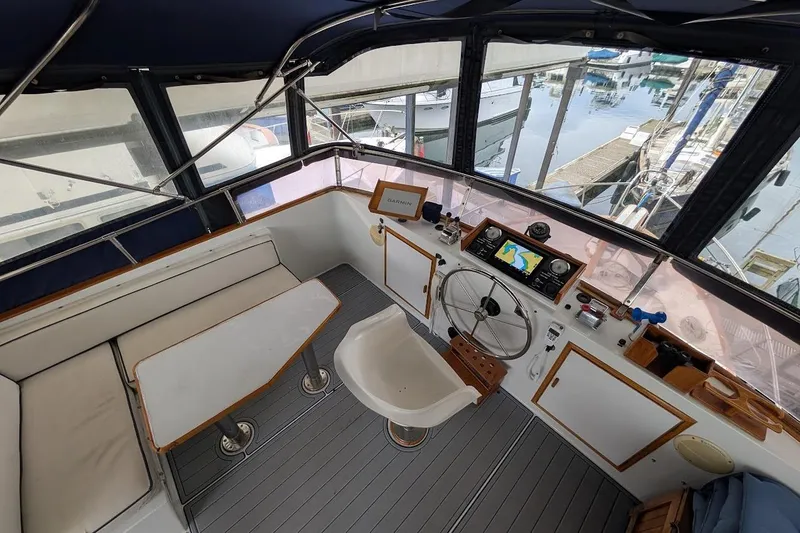 Slide: The Image of 1987 DeFever Trawler helm with navigation equipment, seating, and marina view. - 32