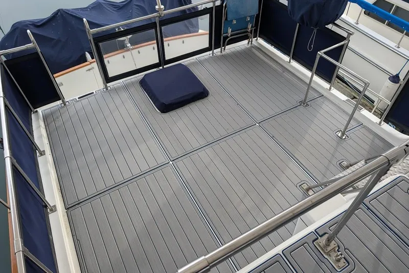 Slide: The Image of 1987 DeFever Trawler deck with gray flooring and stainless steel railings. - 36
