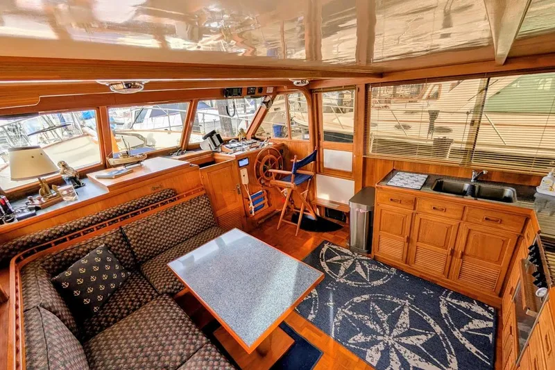 Slide: The Image of 1987 DeFever Trawler interior with wooden decor, seating area, helm, and kitchenette. - 5