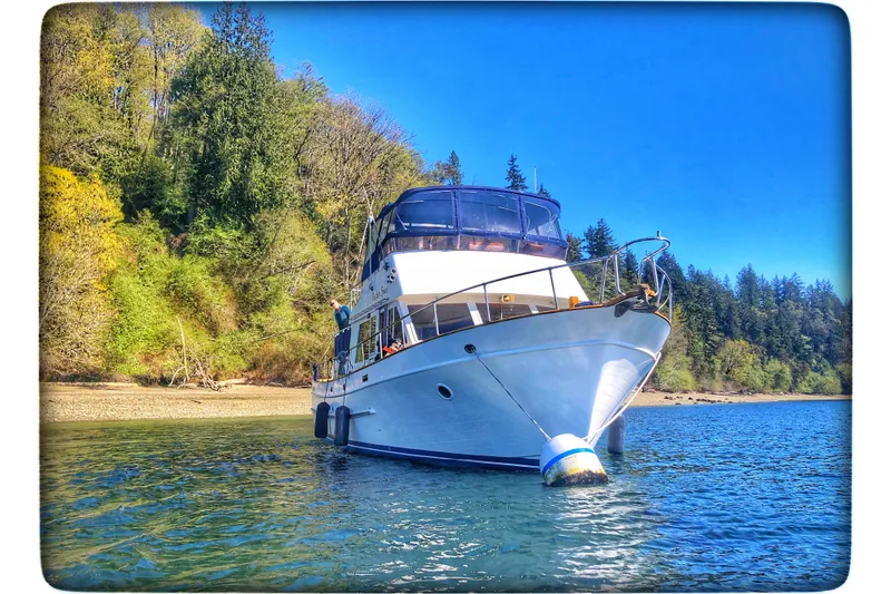 Slide: The Image of 1987 DeFever Trawler anchored in scenic, forested waters under a clear blue sky. - 51