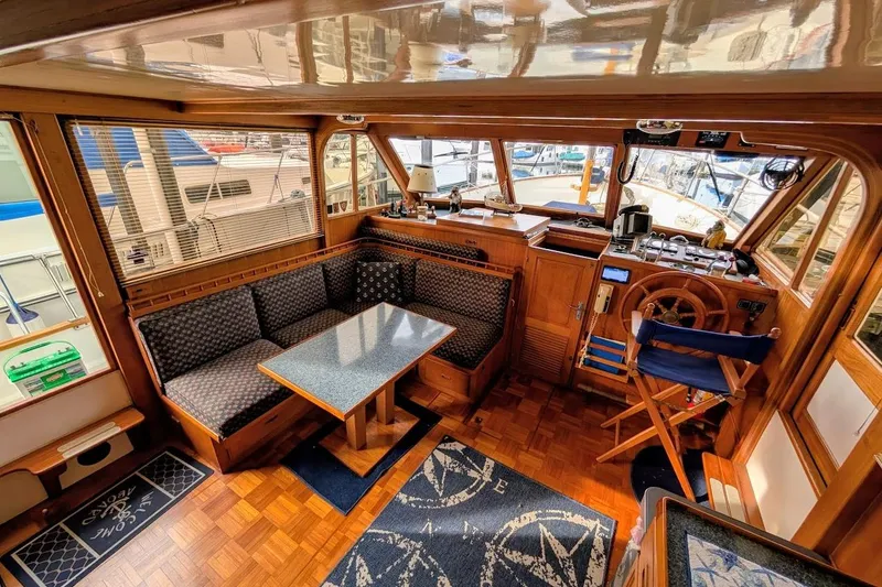 Slide: The Image of 1987 DeFever Trawler interior with wooden helm, dining area, and nautical decor. - 6