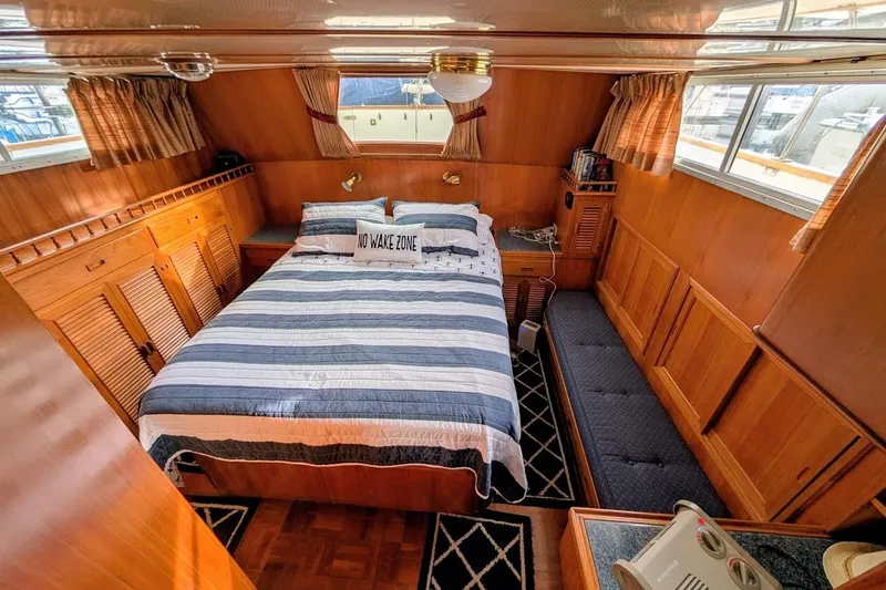 Slide: The Image of 1987 DeFever Trawler cabin with striped bedding, wood paneling, and "No Wake Zone" pillow. - 14