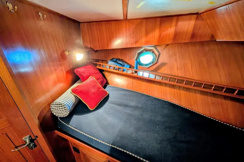 Slide: The Image of 1987 DeFever Trawler cabin with cozy bed, wooden interior, and nautical decor. - 26