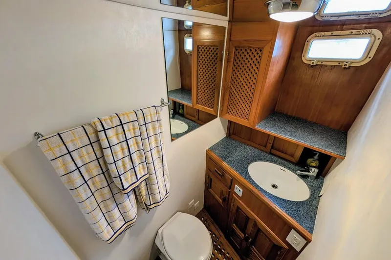 Slide: The Image of 1987 DeFever Trawler bathroom with wooden cabinets, sink, and checkered towels. - 27