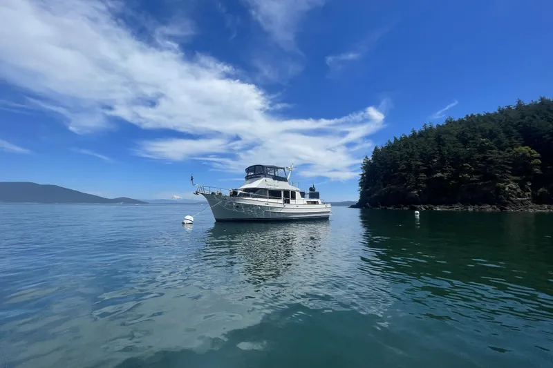 Slide: The Image of 1987 DeFever Trawler anchored in serene waters, surrounded by lush greenery and blue skies. - 52