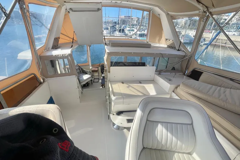 Slide: The Image of 1986 Hi-Star Aft Cabin yacht interior with white seating and marina view. - 10