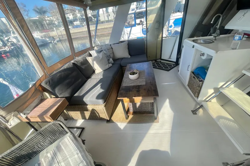 Slide: The Image of 1986 Hi-Star Aft Cabin interior with cozy seating, wooden table, and marina view. - 16