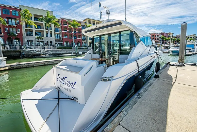 Slide: The Image of 2017 Tiara Yacht Coupe docked at marina, surrounded by colorful buildings and palm trees. - 4