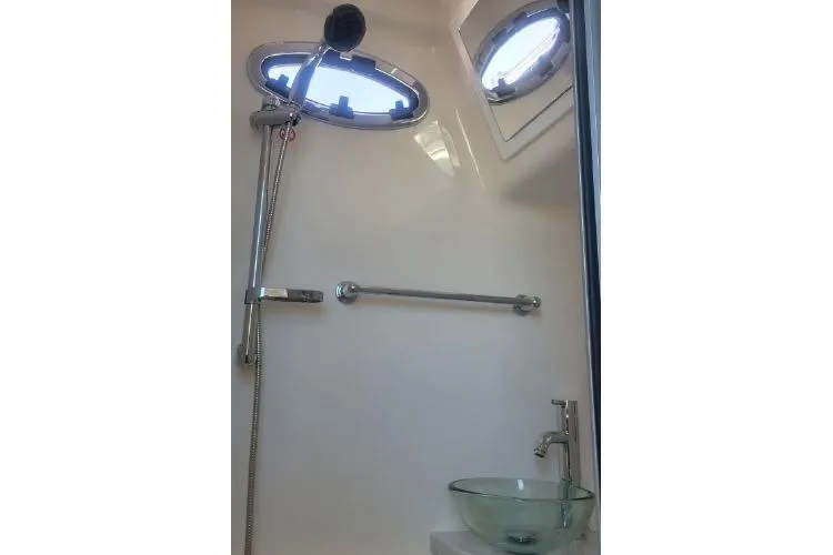 Slide: The Image of 2022 Regulator 41 boat bathroom with shower, glass sink, and porthole windows. - 37
