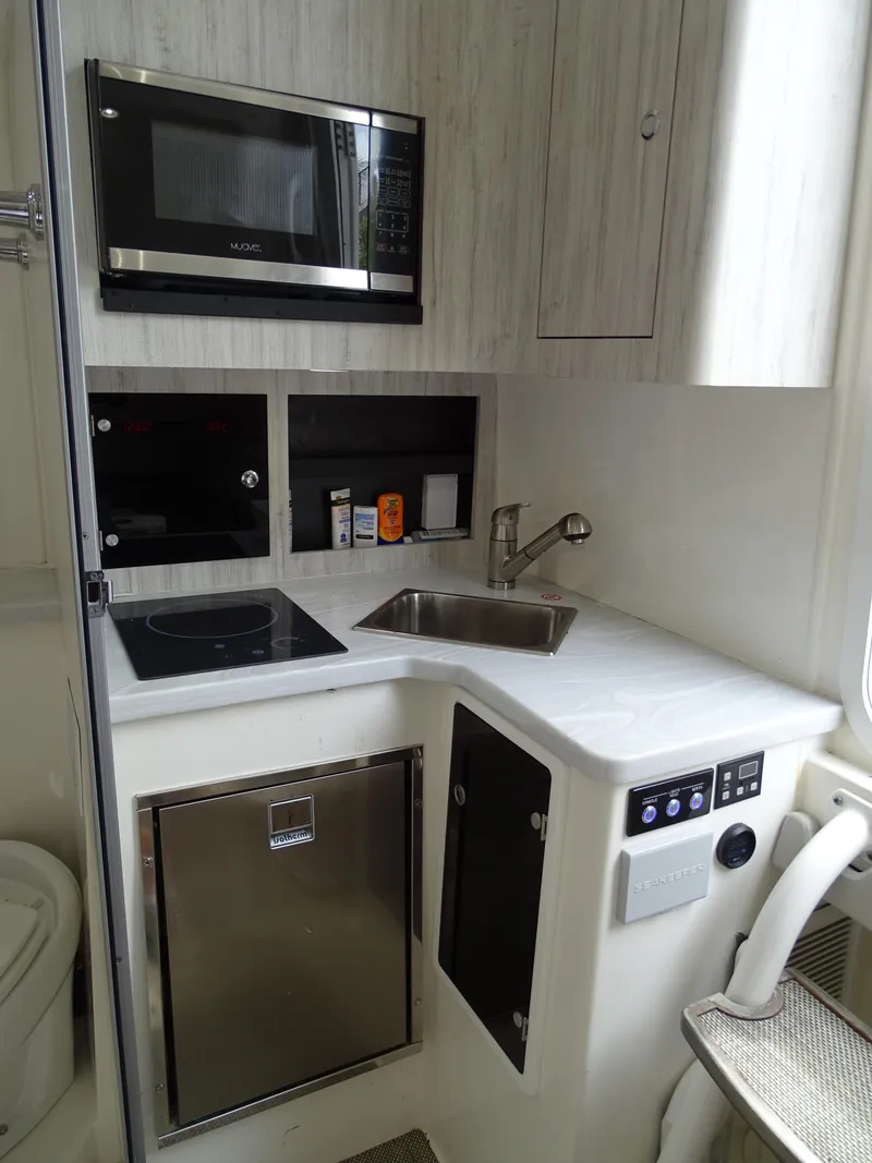 Slide: The Image of Compact kitchen area in 2022 Regulator 41 boat with microwave, sink, and mini fridge. - 38