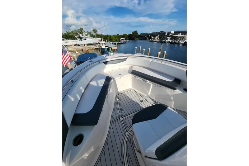 Slide: The Image of 2019 Robalo R242 Center Console boat interior with seating, docked by a marina. - 10