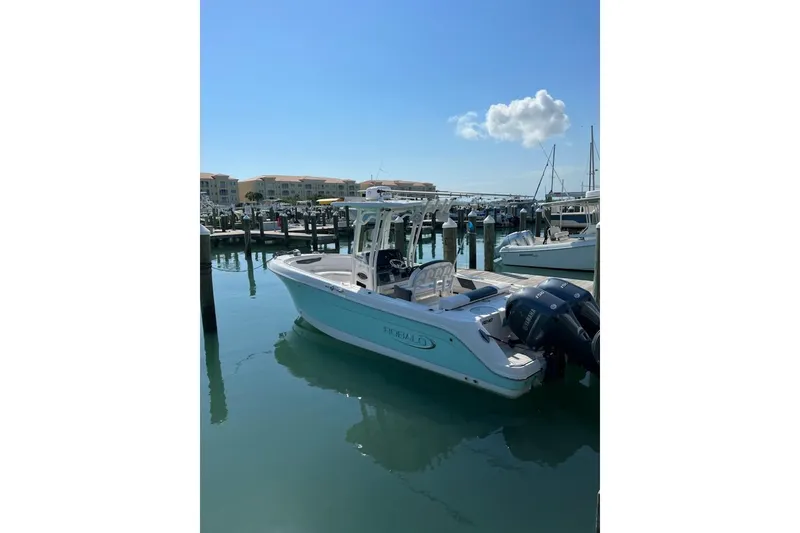 Slide: The Image of 2019 Robalo R242 Center Console boat docked in a sunny marina. - 2