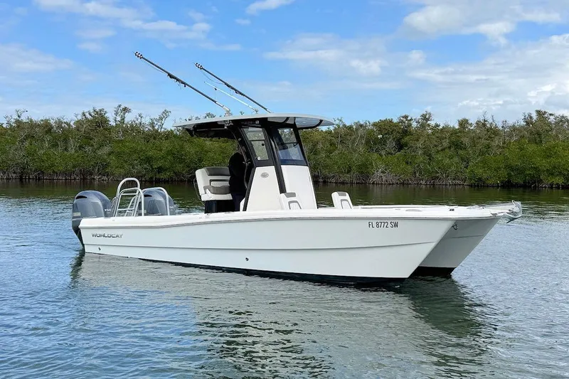 Slide: The Image of 2021 World Cat 235 CC boat on calm water, featuring dual engines and fishing rods. - 2