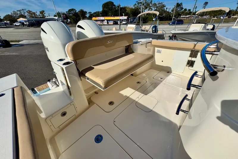 Slide: The Image of 2021 Scout 277 LXF boat interior with seating and dual engines, docked outdoors. - 13