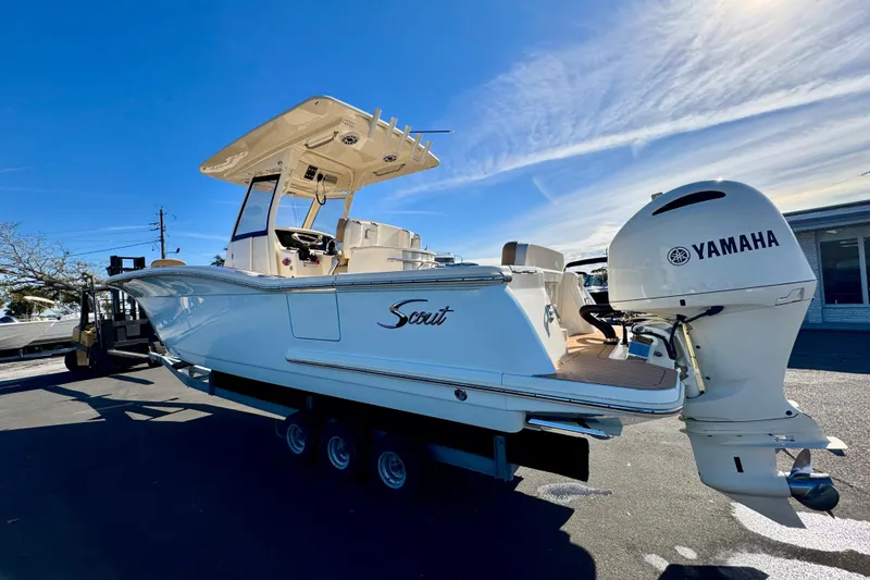 Slide: The Image of 2021 Scout 277 LXF boat with Yamaha engine, parked outdoors under clear blue sky. - 4
