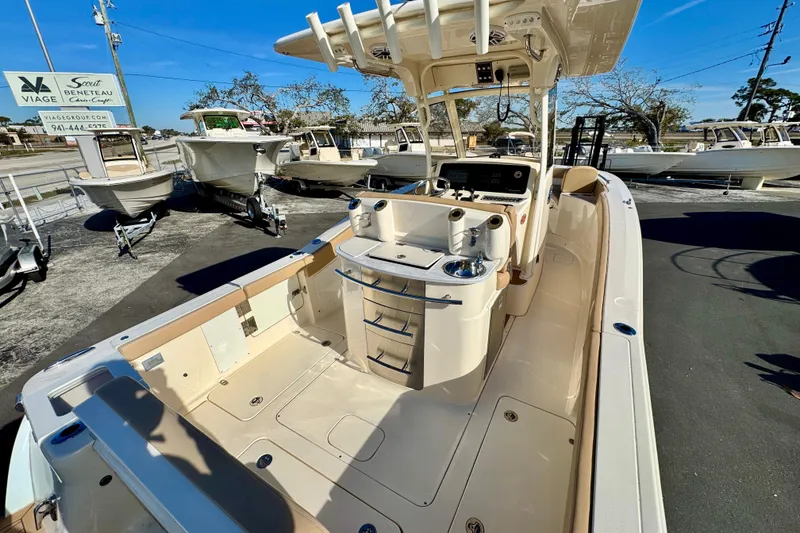 Slide: The Image of 2021 Scout 277 LXF boat interior with helm, seating, and storage, displayed at a dealership. - 9