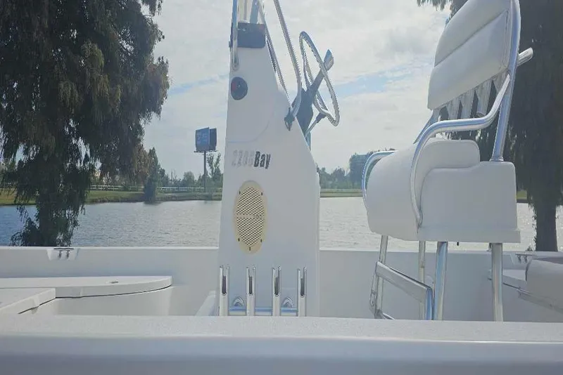 Slide: The Image of 2009 Ranger 2200 Bay boat interior with steering wheel and seating by a lake. - 2