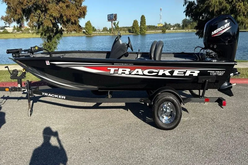 Slide: The Image of 2026 Bass Tracker Pro Team 175 boat on trailer by a lake, sunny day. - 4