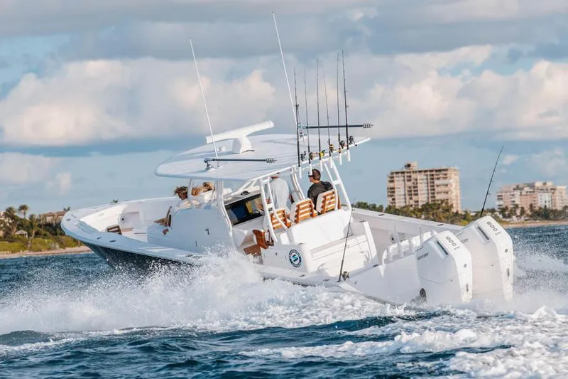 Slide: The Image of Manufacturer Provided Image: 2026 Jupiter 40 boat cruising on ocean with fishing rods, cityscape in background. - 2