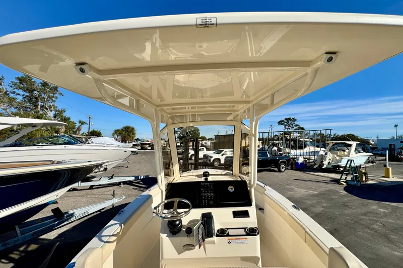 Slide: The Image of 2026 Scout 240 XSF boat interior with helm, parked in marina under clear blue sky. - 12
