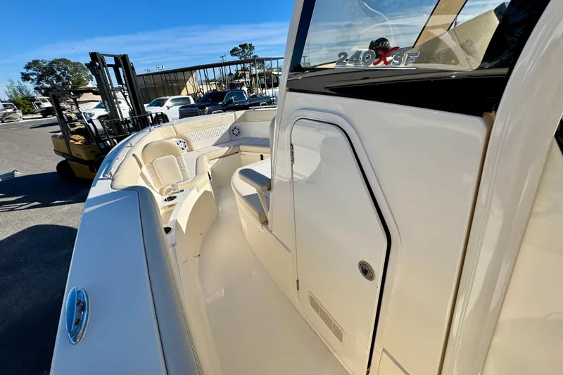 Slide: The Image of 2026 Scout 240 XSF boat interior with seating and storage, parked outdoors. - 16