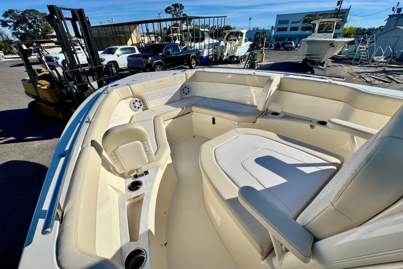 Slide: The Image of 2026 Scout 240 XSF boat interior with luxurious seating and cup holders in a marina setting. - 17