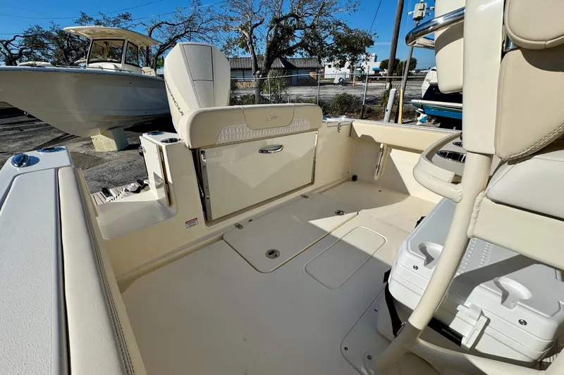 Slide: The Image of 2026 Scout 240 XSF boat interior with seating and storage, docked outdoors. - 8