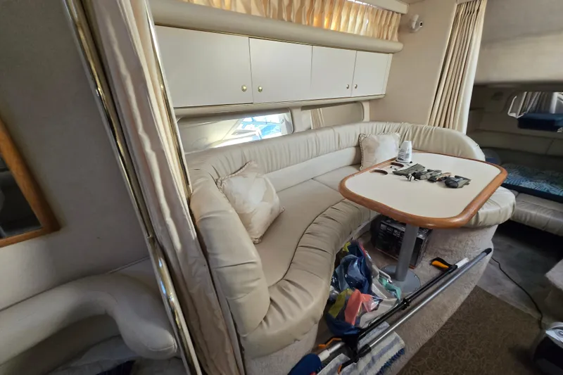 Slide: The Image of 1999 Sea Ray 340 Sundancer interior with beige seating and table, showcasing cozy cabin space. - 17