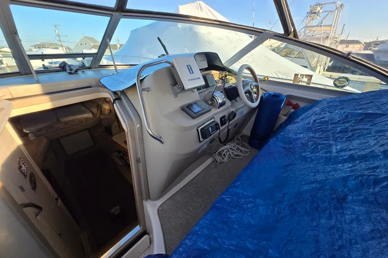 Slide: The Image of 1999 Sea Ray 340 Sundancer cockpit with steering wheel, navigation equipment, and blue tarp. - 19