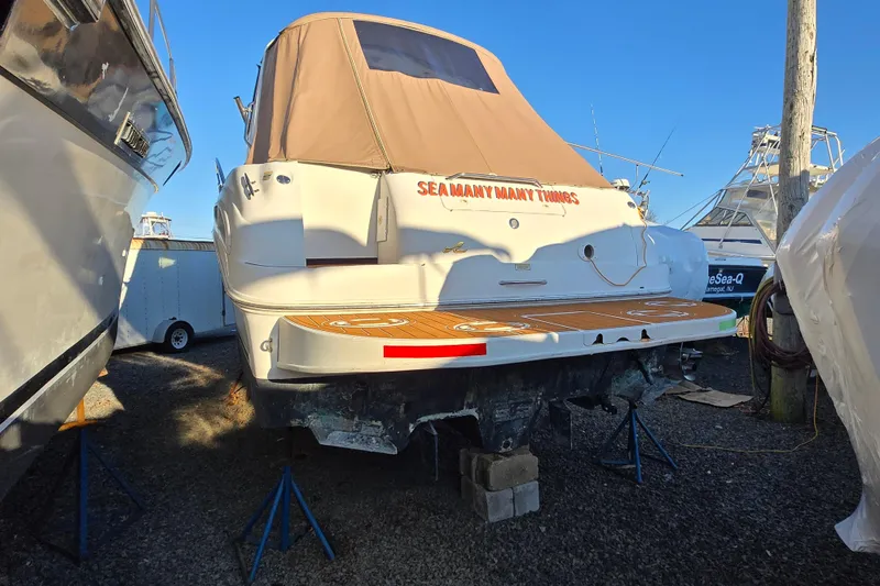 Slide: The Image of 1999 Sea Ray 340 Sundancer boat on stands, covered, in a marina setting. - 24