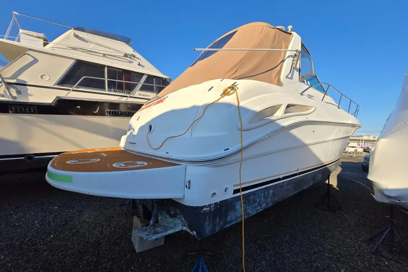 Slide: The Image of 1999 Sea Ray 340 Sundancer boat on stands, with a covered deck, in a marina. - 5