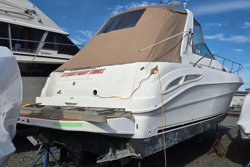 Slide: The Image of 1999 Sea Ray 340 Sundancer boat in storage, covered and elevated, with clear sky background. - 9