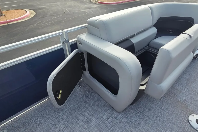 Slide: The Image of 2026 Sun Tracker SportFish 22 DLX pontoon boat with open storage compartment and cushioned seating. - 11